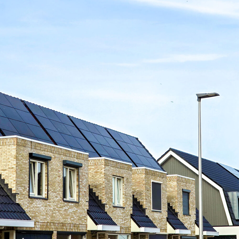 Dutch Suburban area with modern family houses with black solar panels on the roof against a sunny sk,. Zonnepanelen, Zonne energie, Translation: Solar panel, Sun Energy